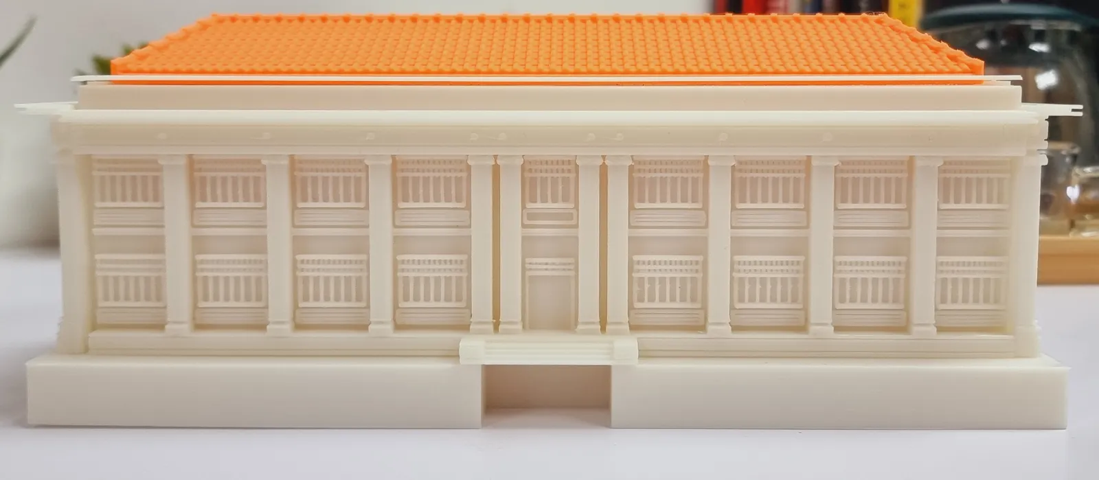 Front of a cream filament-printed heritage building model under an orange tiled roof, its columns and two storeys of balcony railings printed crisp and even