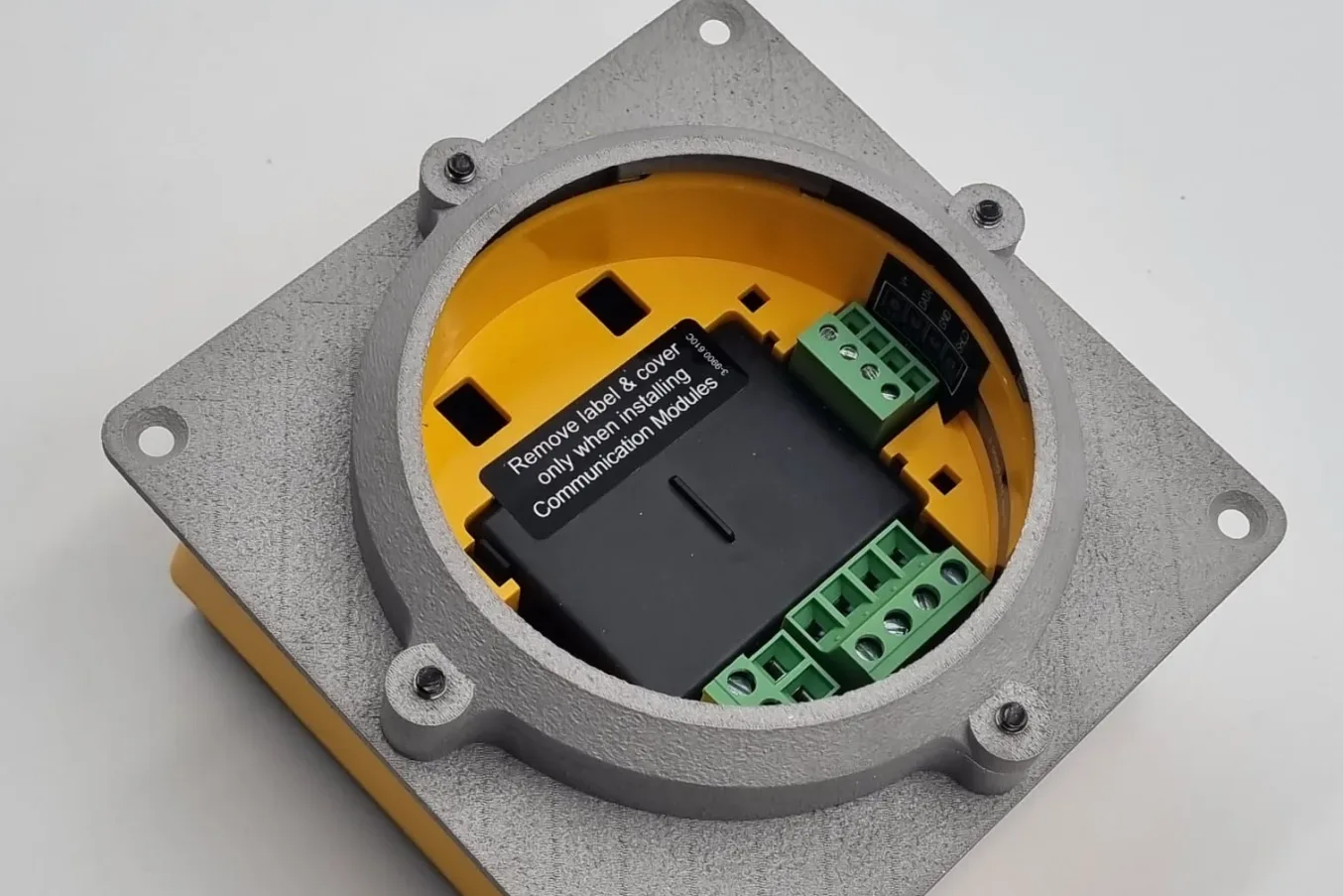 A grey metal 3D printed panel mount bolted around a yellow industrial flow meter, its ring and four screw bosses printed in one piece