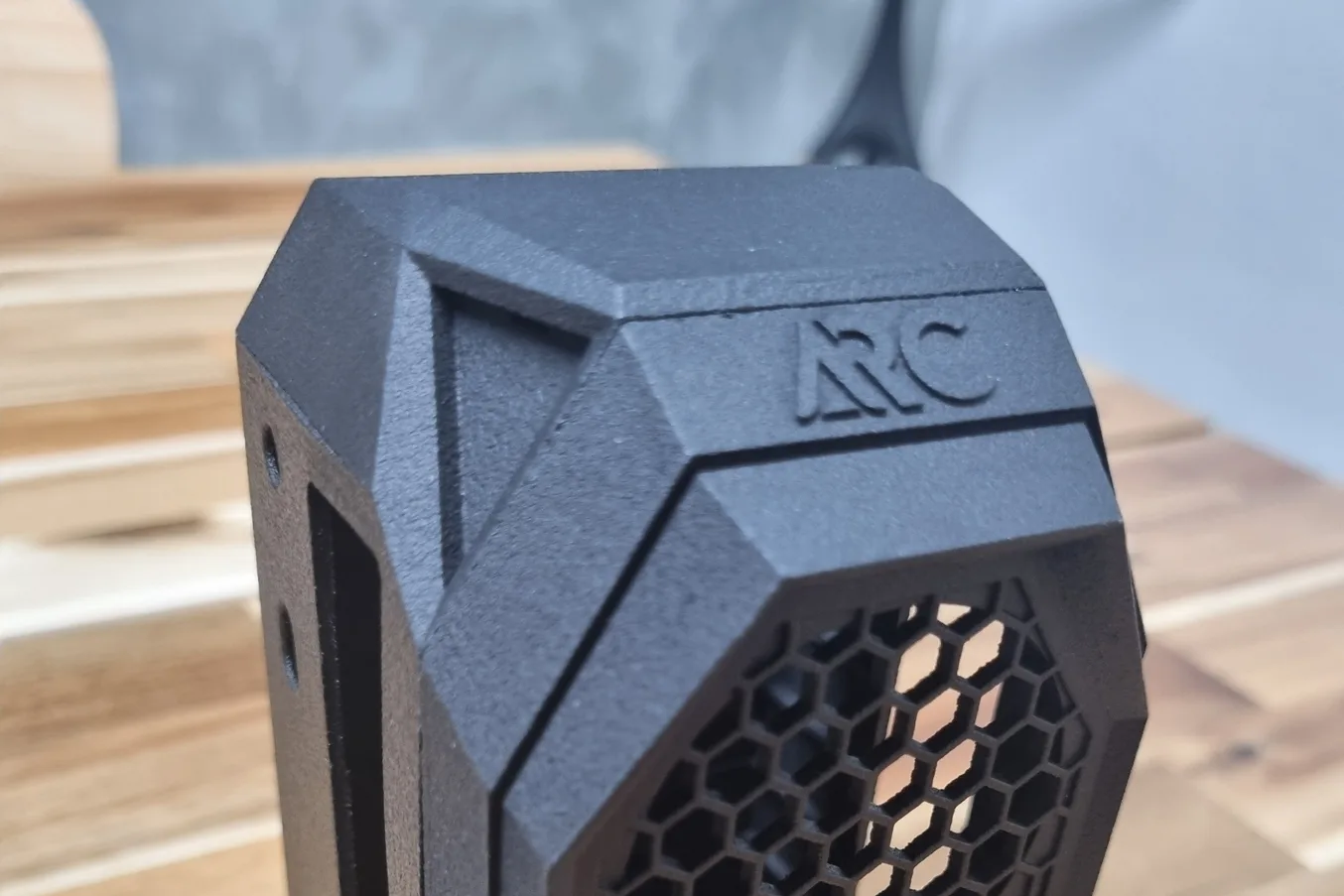 A black nylon case with raised lettering on its top edge, a recessed triangular panel and a fine honeycomb grille on the front