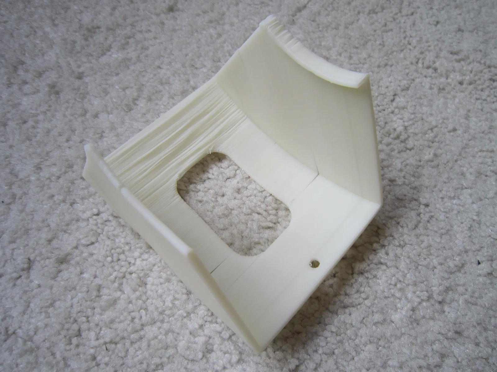 The underside of a curved printed part where an unsupported overhang has sagged into rough, stringy layers