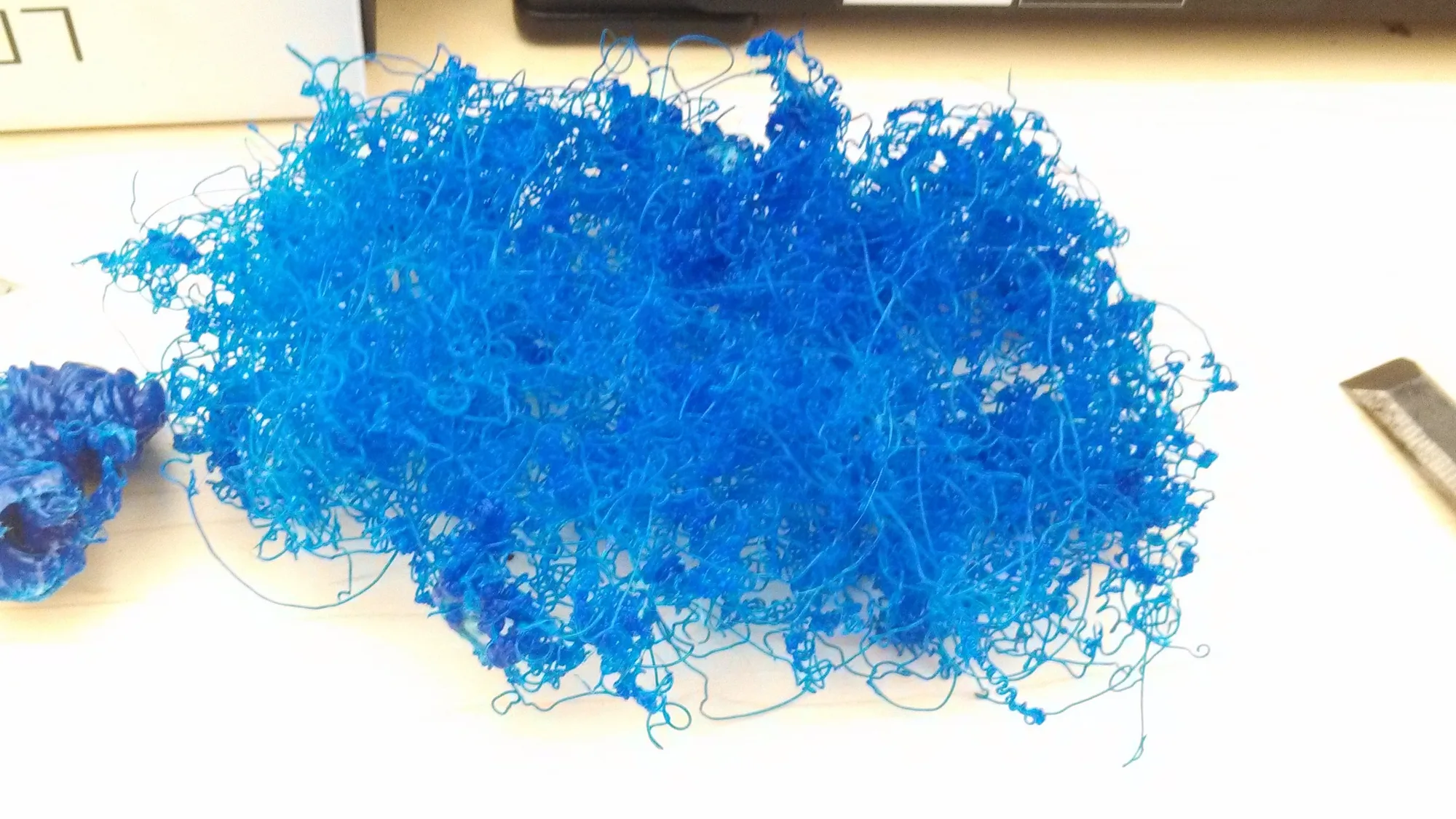 A tangled ball of blue filament on a desk, the mess left when a 3D print goes wrong