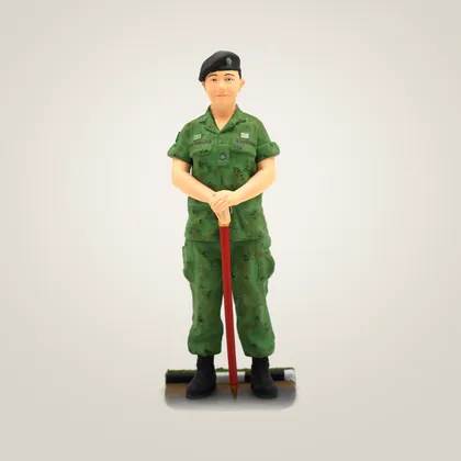 A hand-painted figurine of a woman in army camouflage and a beret, resting on a cane