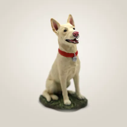 A hand-painted cream dog figurine in a red collar, sitting on a grass base