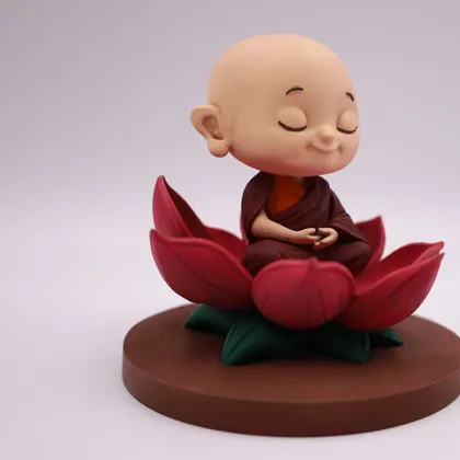 A chibi monk figurine meditating on a hand-painted lotus base