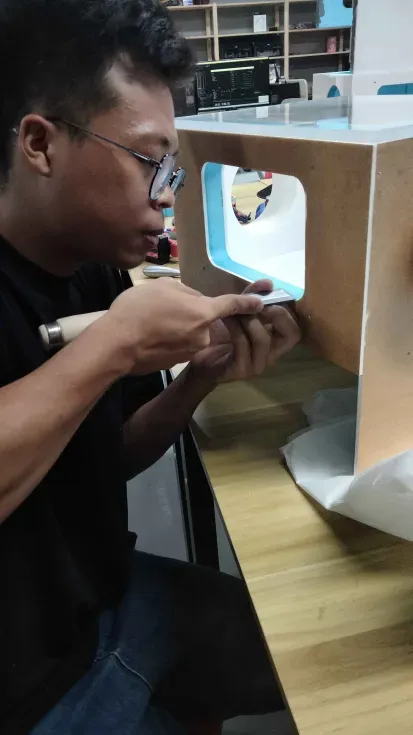 A team member trimming the edge of the window opening with a chisel, the acrylic and blue foam layers showing at the cut