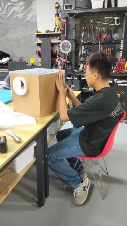 A team member at the workbench pressing the panels of the closed box square, a glove port on the face towards him