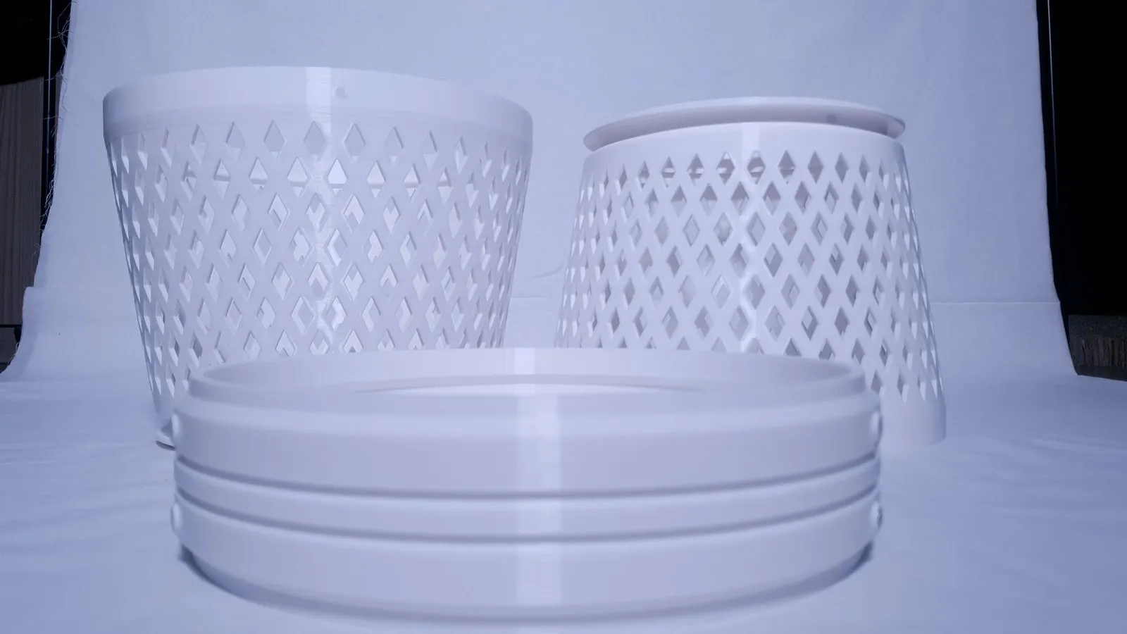 The printed white parts on a white backdrop: two diamond-lattice housing halves and a stack of locking rings