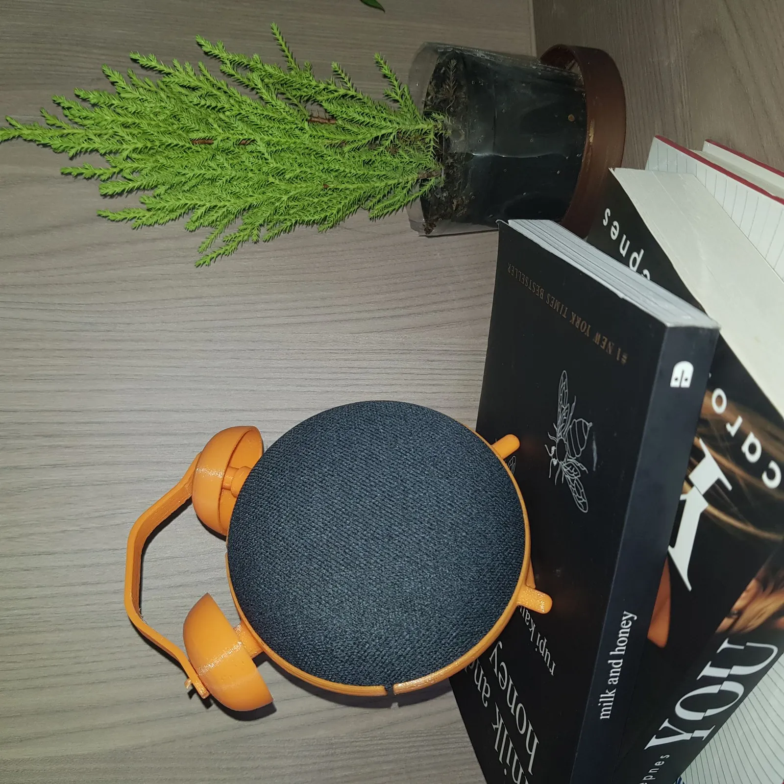 The finished stand from above on a wooden table, beside a stack of books and a potted pine