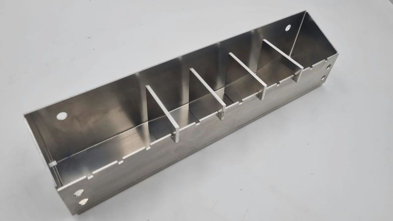 The finished holder from a high corner, its angled end in front and the four dividers running along the tray