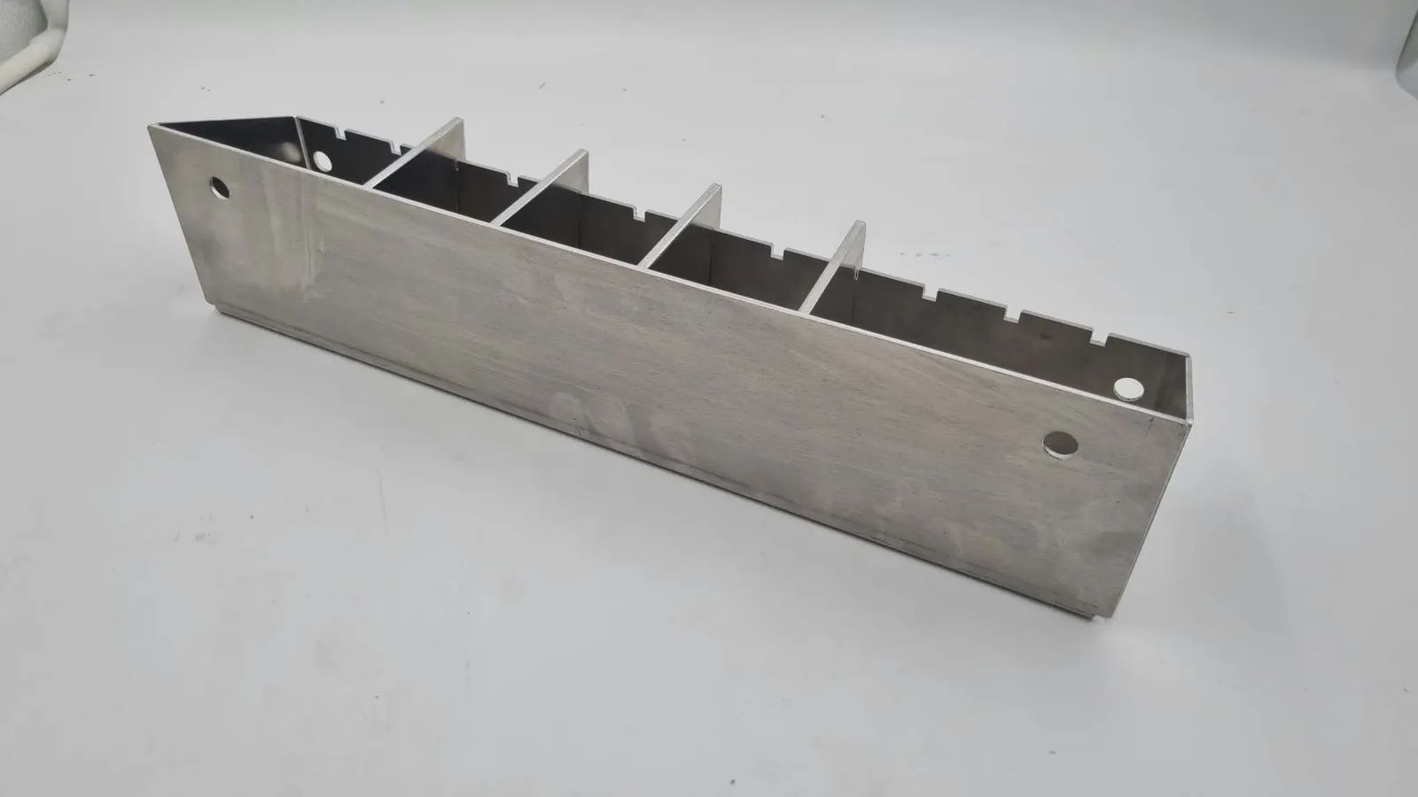 The back of the finished holder: a plain folded aluminium wall with a hole near each end and the dividers showing above it