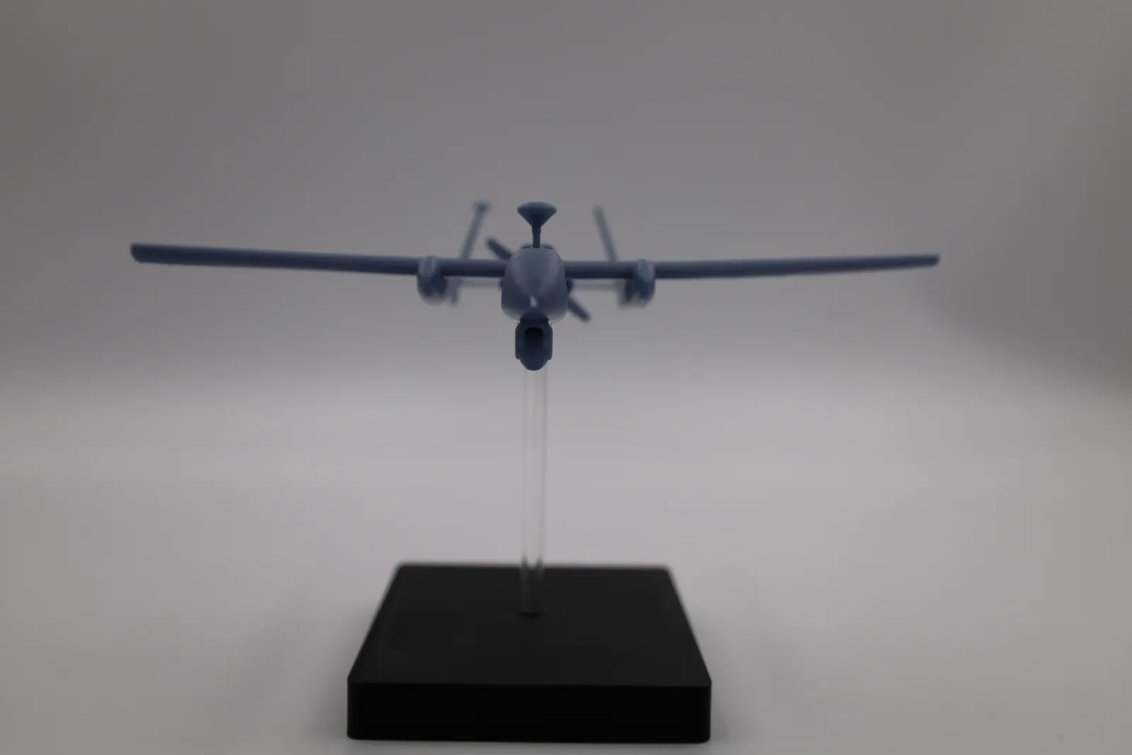 The finished model head-on, its long straight wings level above the clear rod and black base