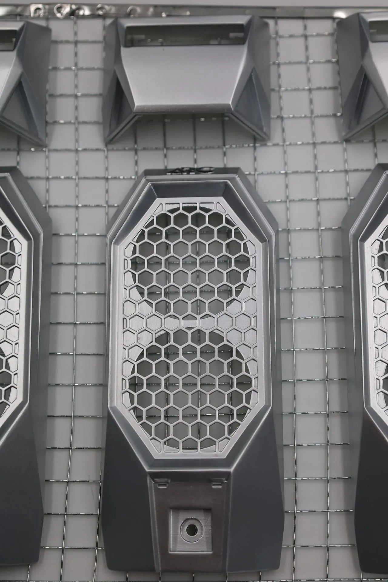 One silver-sprayed front panel on a wire rack, with the ARC lettering above a honeycomb grille over two round fan openings
