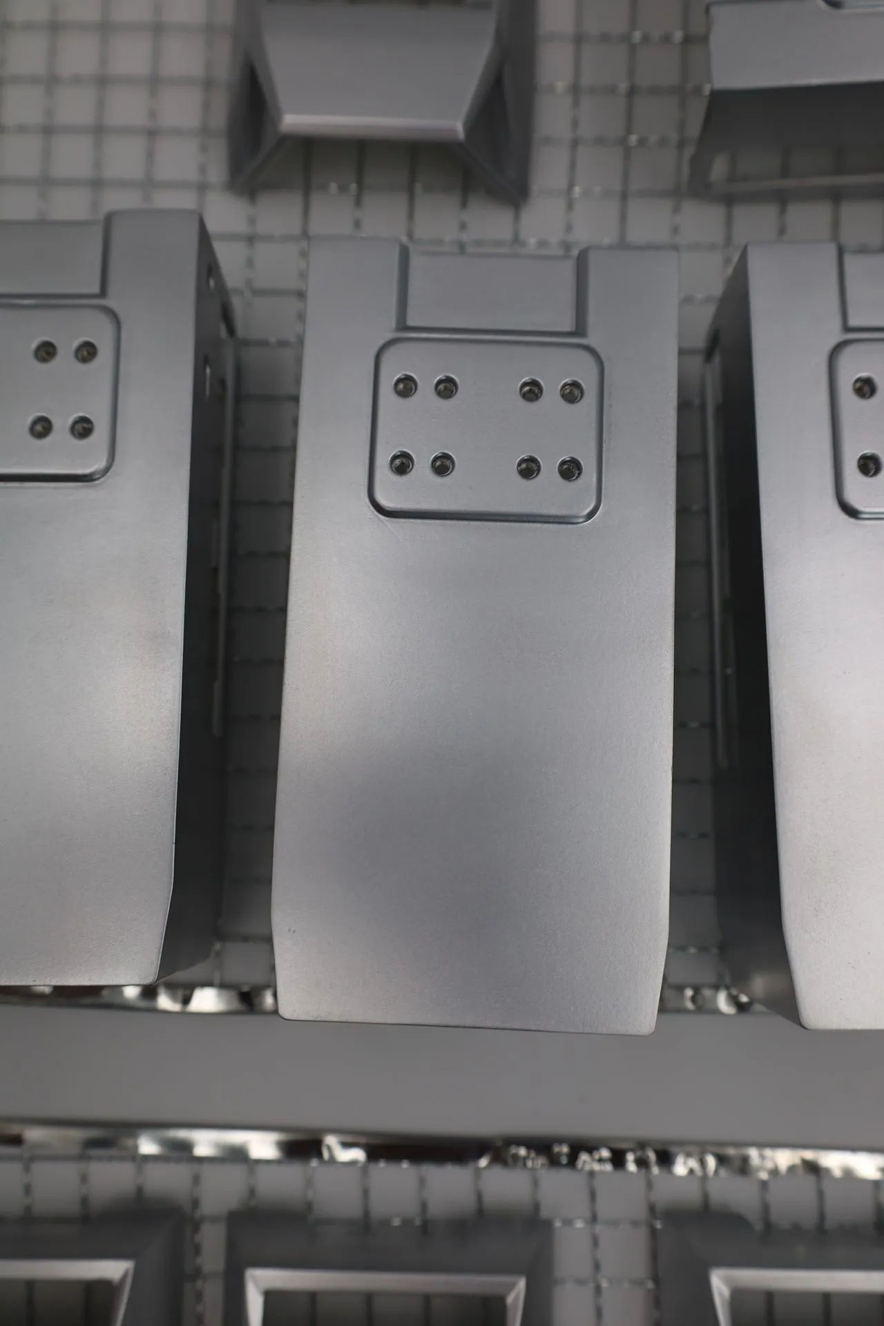 Close-up of a silver-sprayed rear panel with the recessed pad of eight small holes