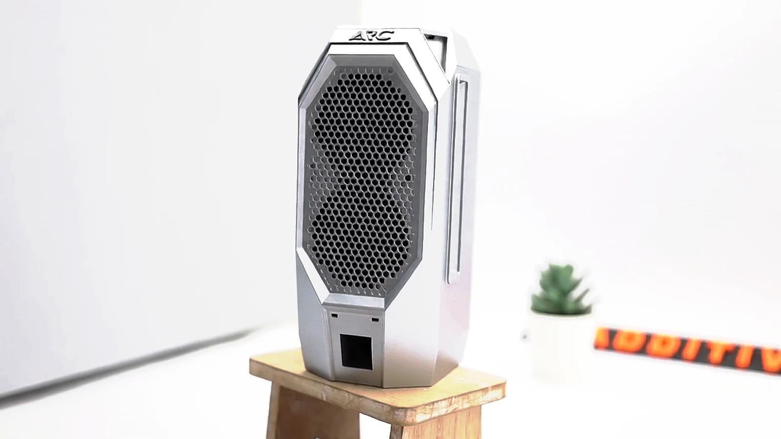 The assembled ARC case in matt silver-grey on a small wooden stand, the raised ARC name on the top cap above the honeycomb front grille