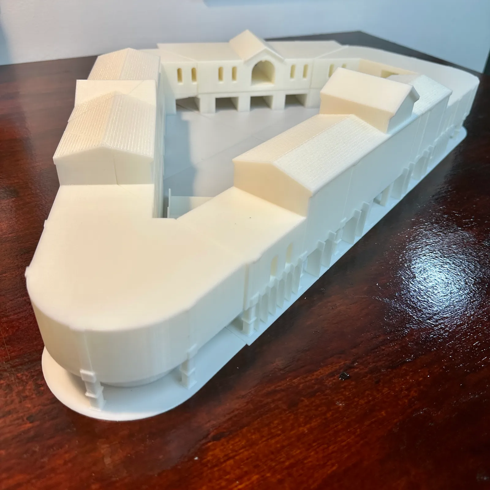 The white building model from a rounded corner, looking over the gabled roofs into the courtyard and across to the central arched pavilion