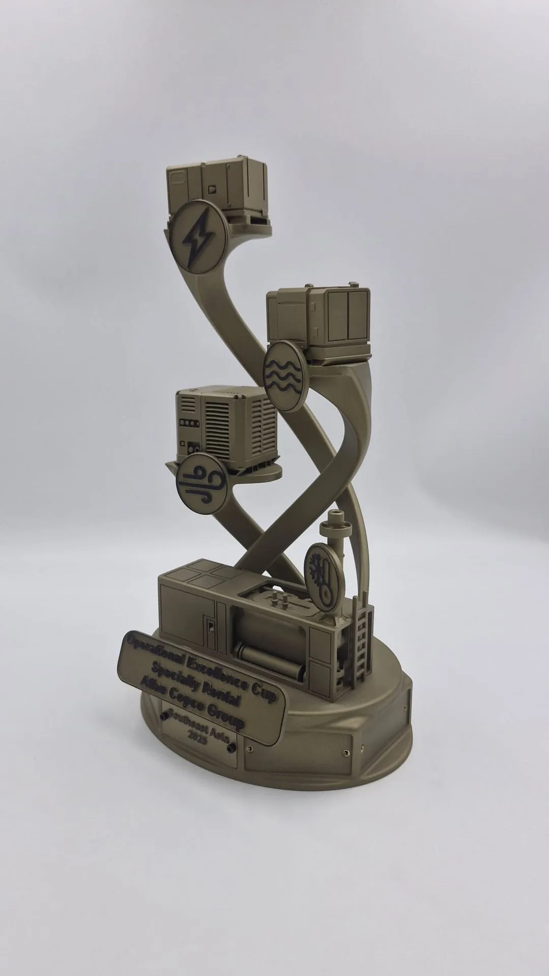 One finished gold trophy turned to the side, showing the twisting arms and the machines stacked up the stand