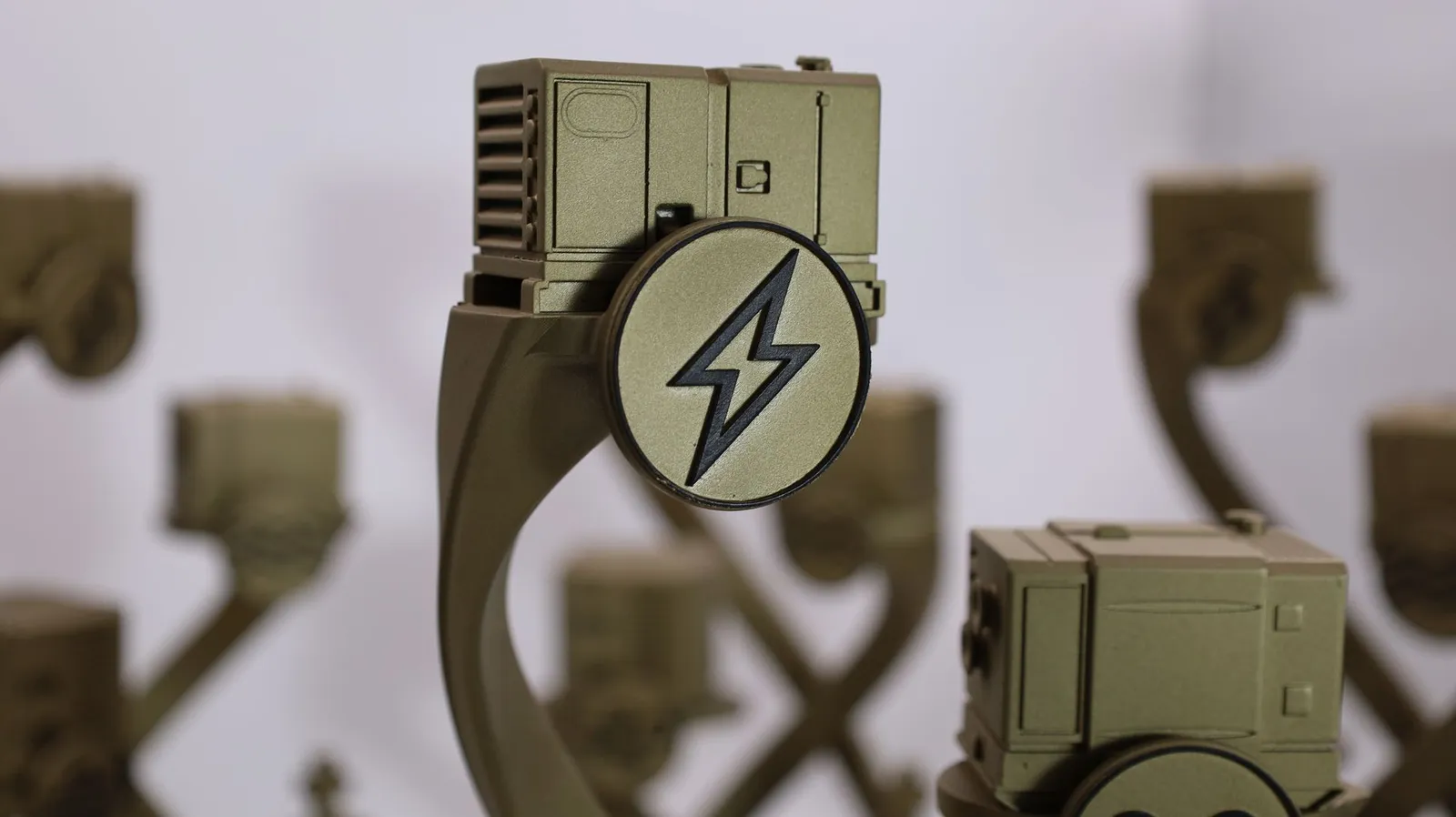 Close-up of a gold miniature machine at the top of the stand, with a disc showing a black lightning bolt