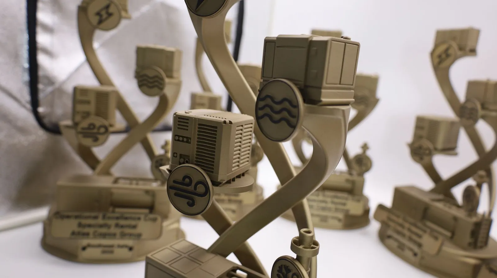 A gold trophy in the foreground with a black wave icon on a disc, other trophies blurred behind it