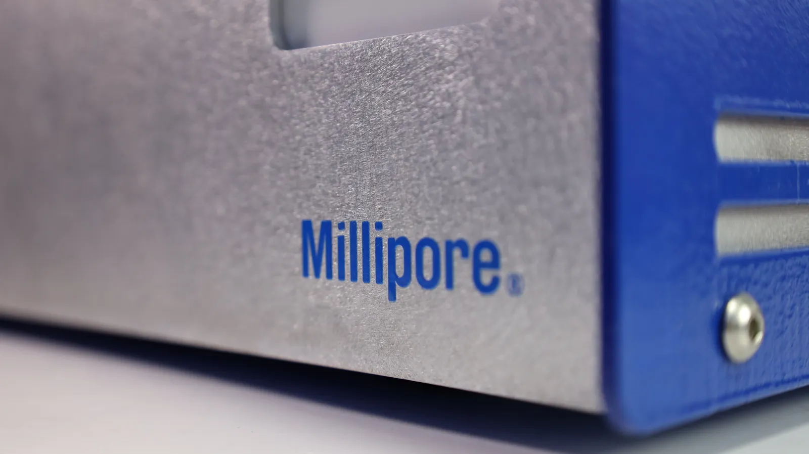 Close-up of the Master Controller's silver front plate with the Millipore lettering and a real screw in the blue side panel