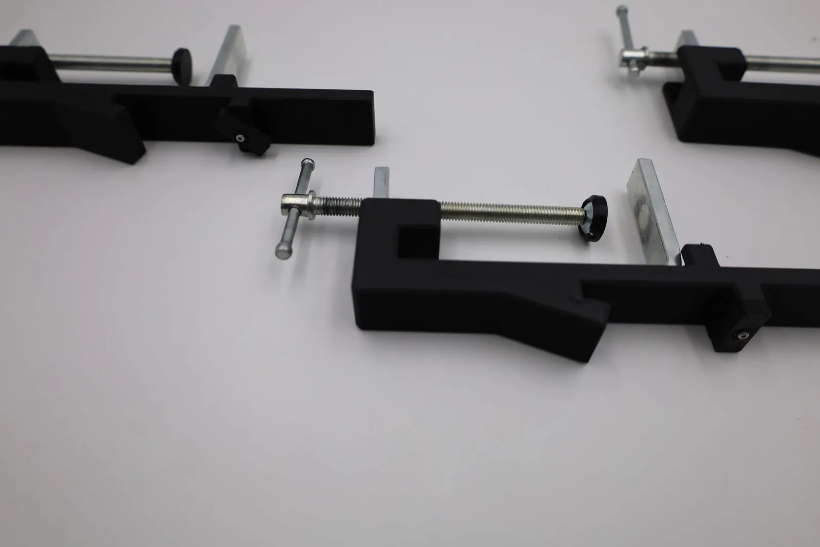 Close-up of a finished clamp: the T-handle screw through the black arm and the small turn latch on top of the arm