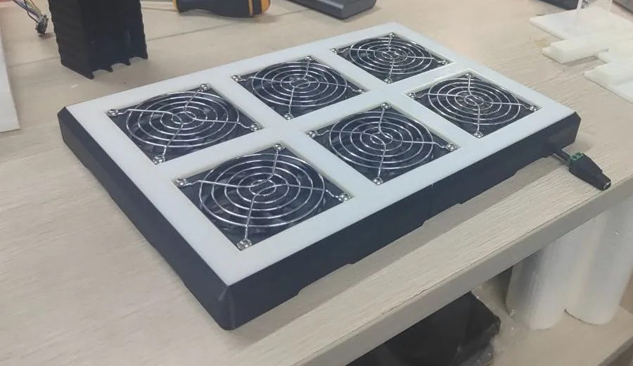 The cooling panel on the workbench before lighting: six fans behind metal grilles in a white frame on a black base