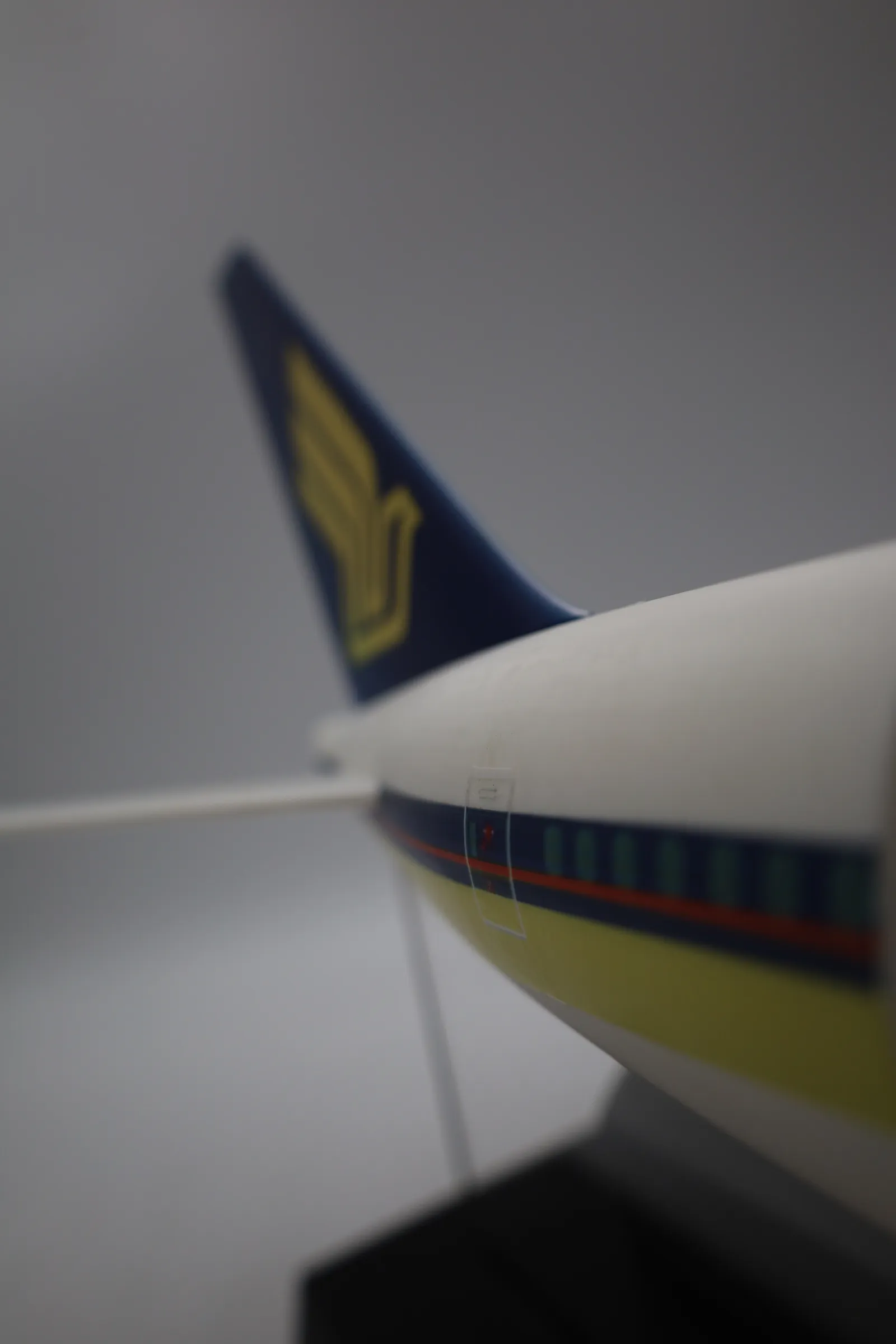 Side view along the white fuselage, showing the blue, red and gold cheatline and window band, held up on clear acrylic