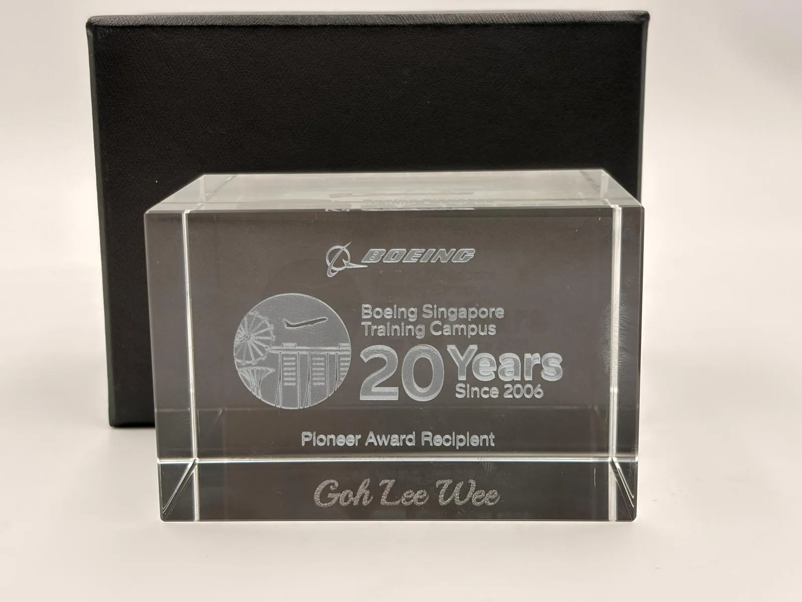 A clear crystal block in front of its black box, showing the Boeing Singapore Training Campus 20 Years artwork, Pioneer Award Recipient and the name Goh Lee Wee in script