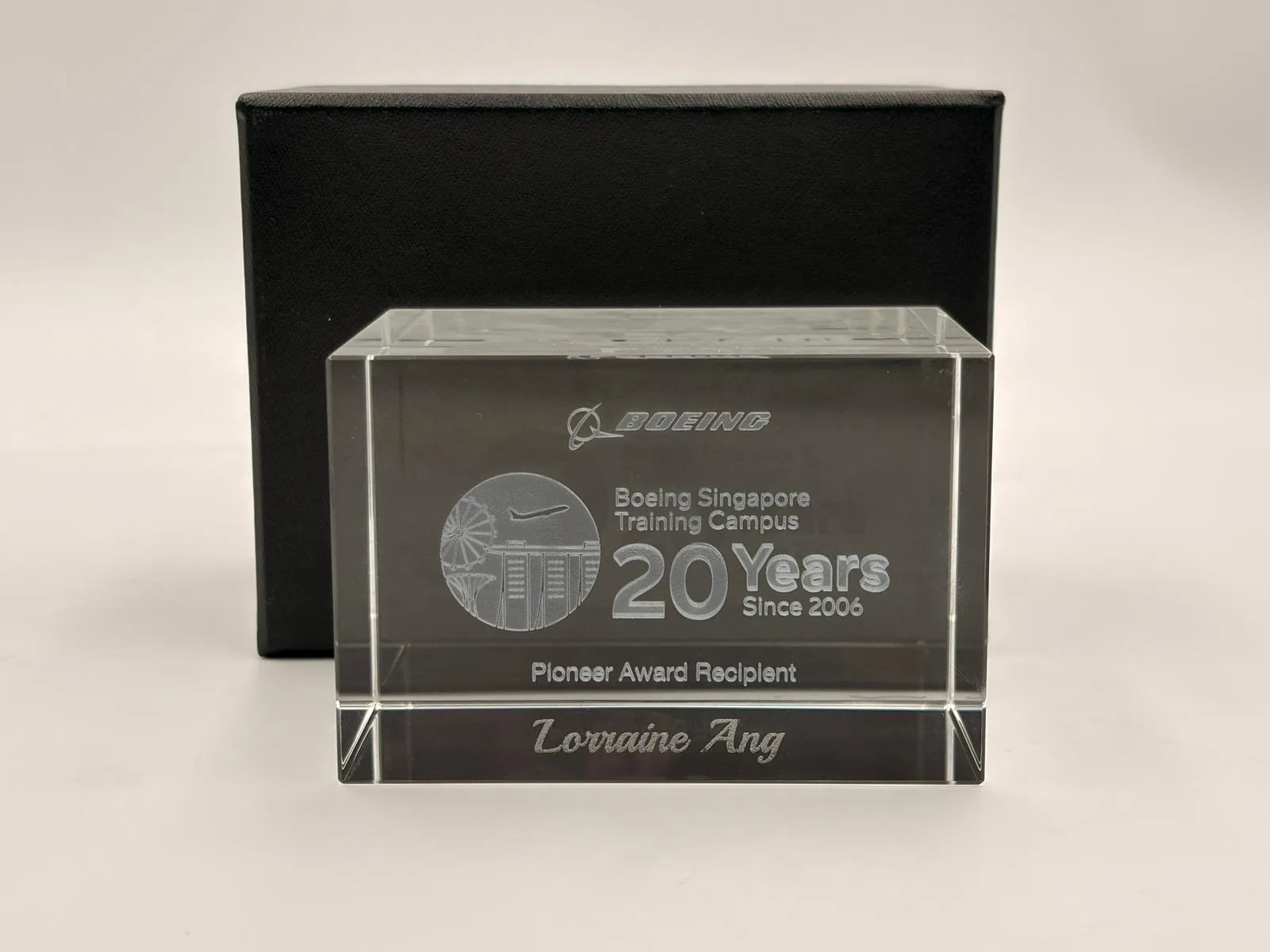 A clear crystal block engraved with the name Lorraine Ang in script below Pioneer Award Recipient