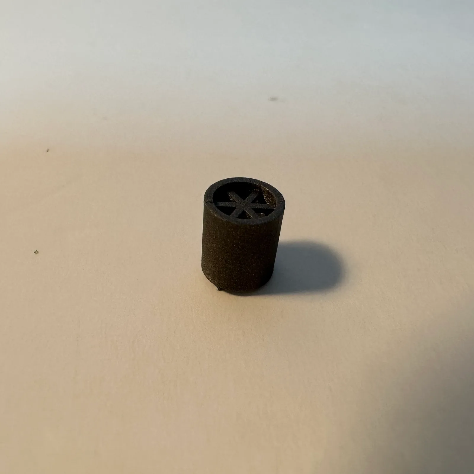 One black spare standing upright on a white table, seen from above at an angle so the six spokes inside its open end show