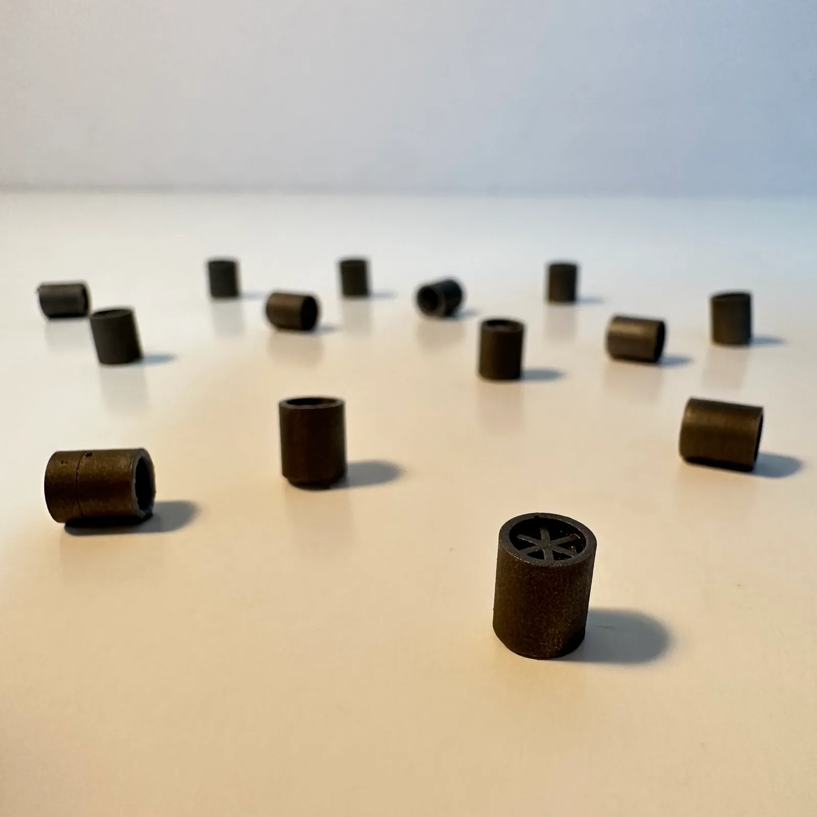 Many of the black spares scattered across a white table, standing and lying in different directions