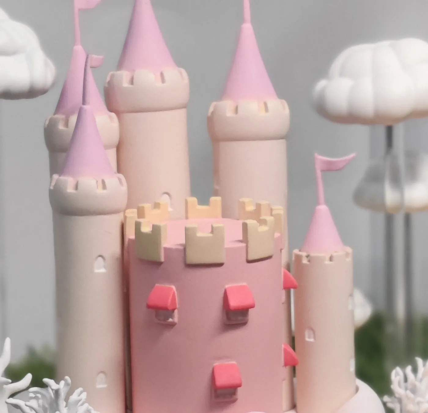 Close-up of the castle's cream towers with pink cone roofs and flags, gold battlements and small red window hoods on the pink keep