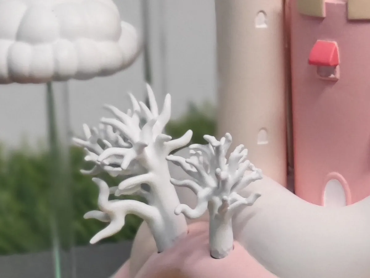 Close-up of two white branching coral trees rising from the pink island beside a castle tower