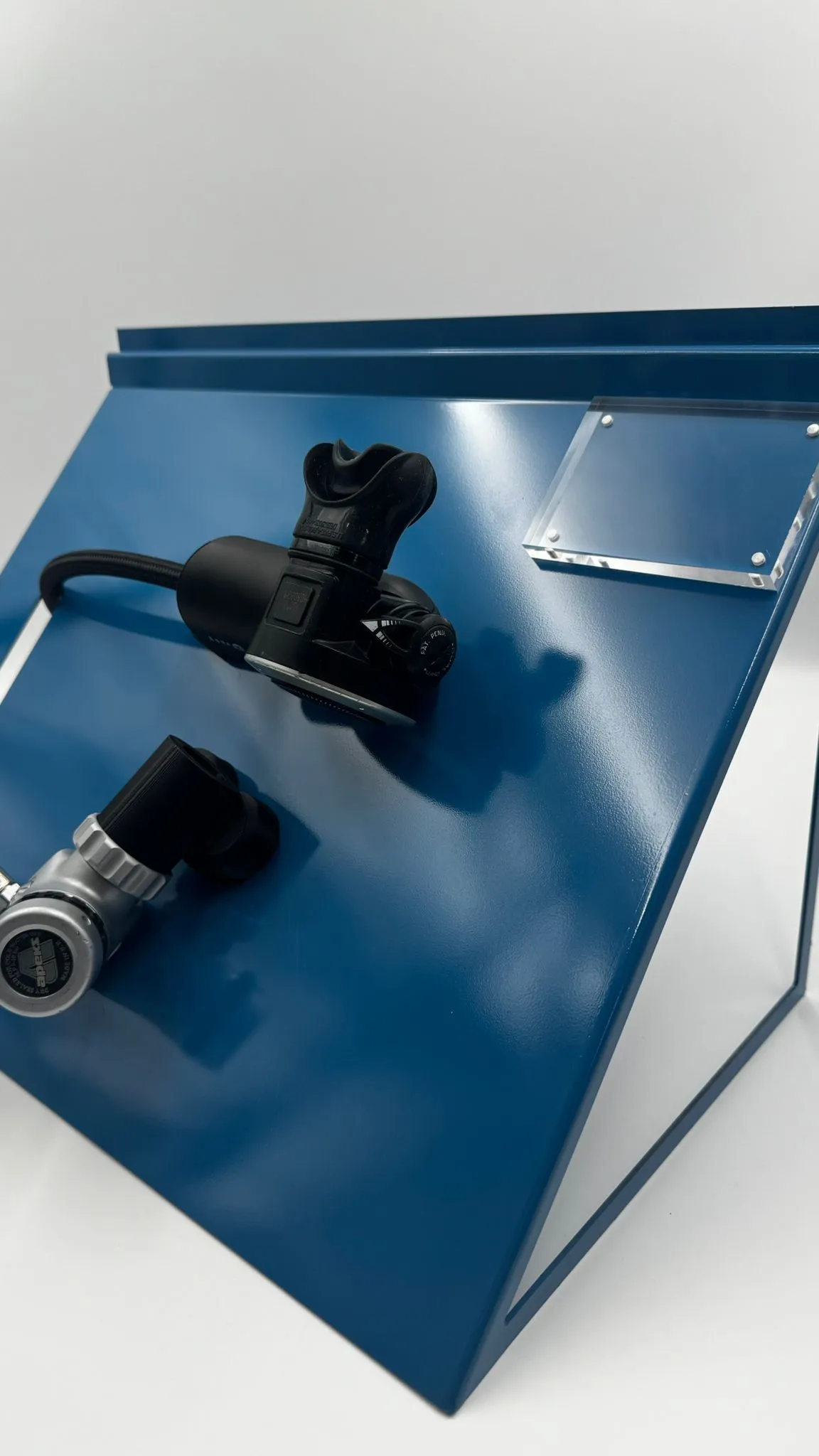 The blue regulator display from the side, showing its triangular steel frame, the regulator on its holders and the acrylic plate