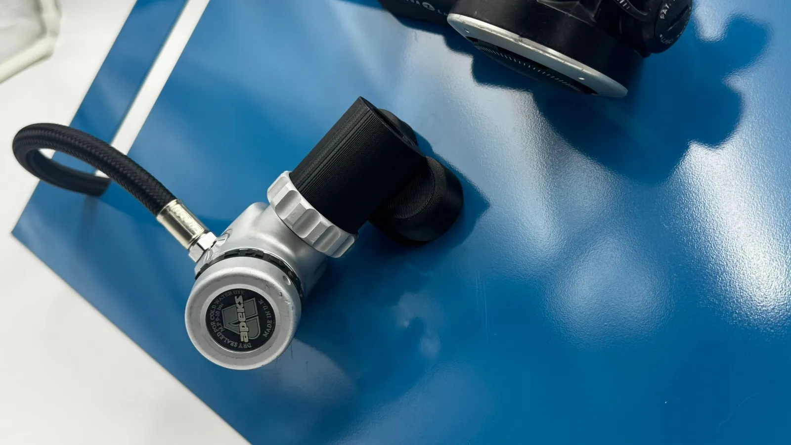 Close-up of the spare regulator held on the blue panel, its hose curving off the edge