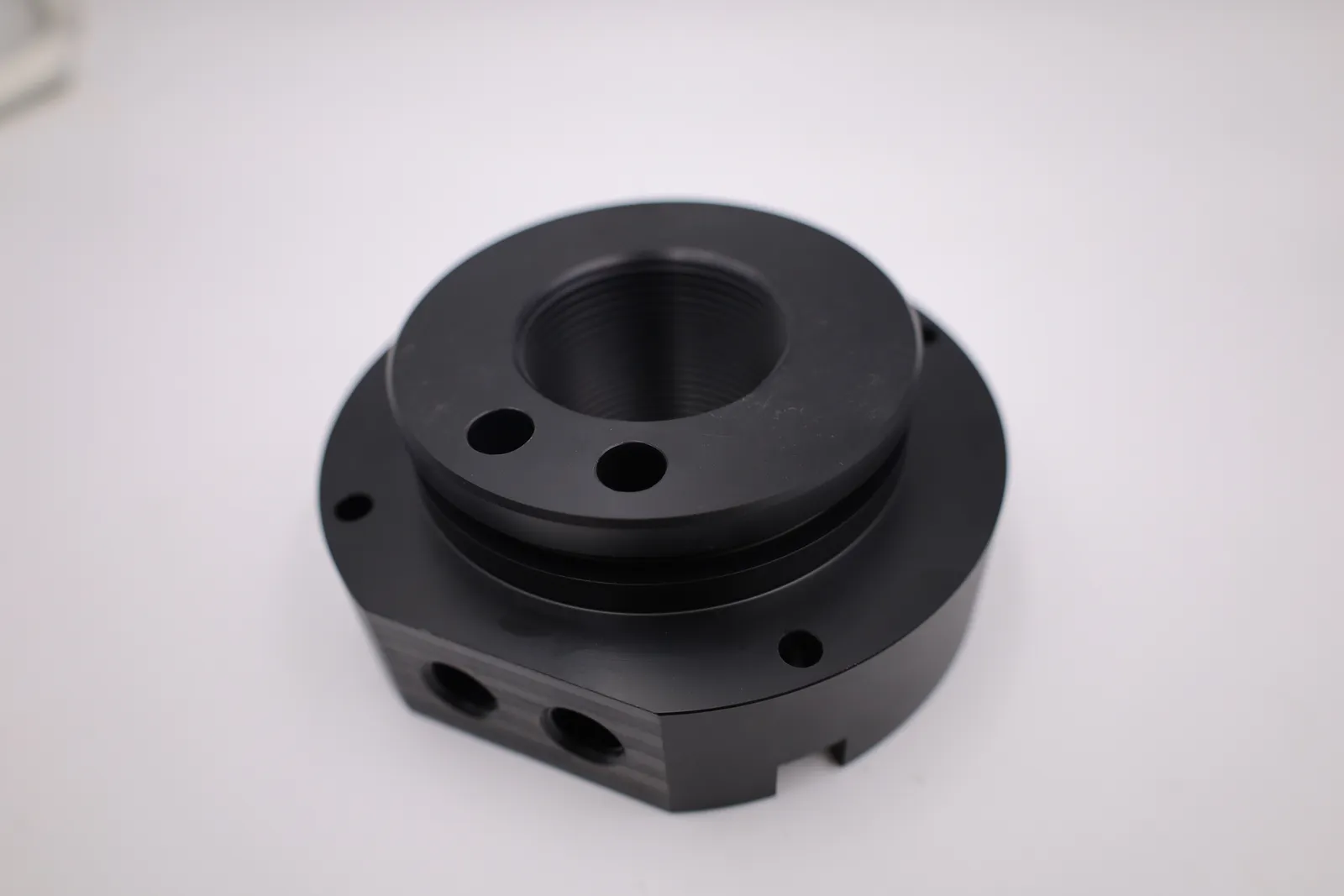 One fuel filling lid from the top: the raised collar with its groove, two holes beside the threaded bore, and the flat side