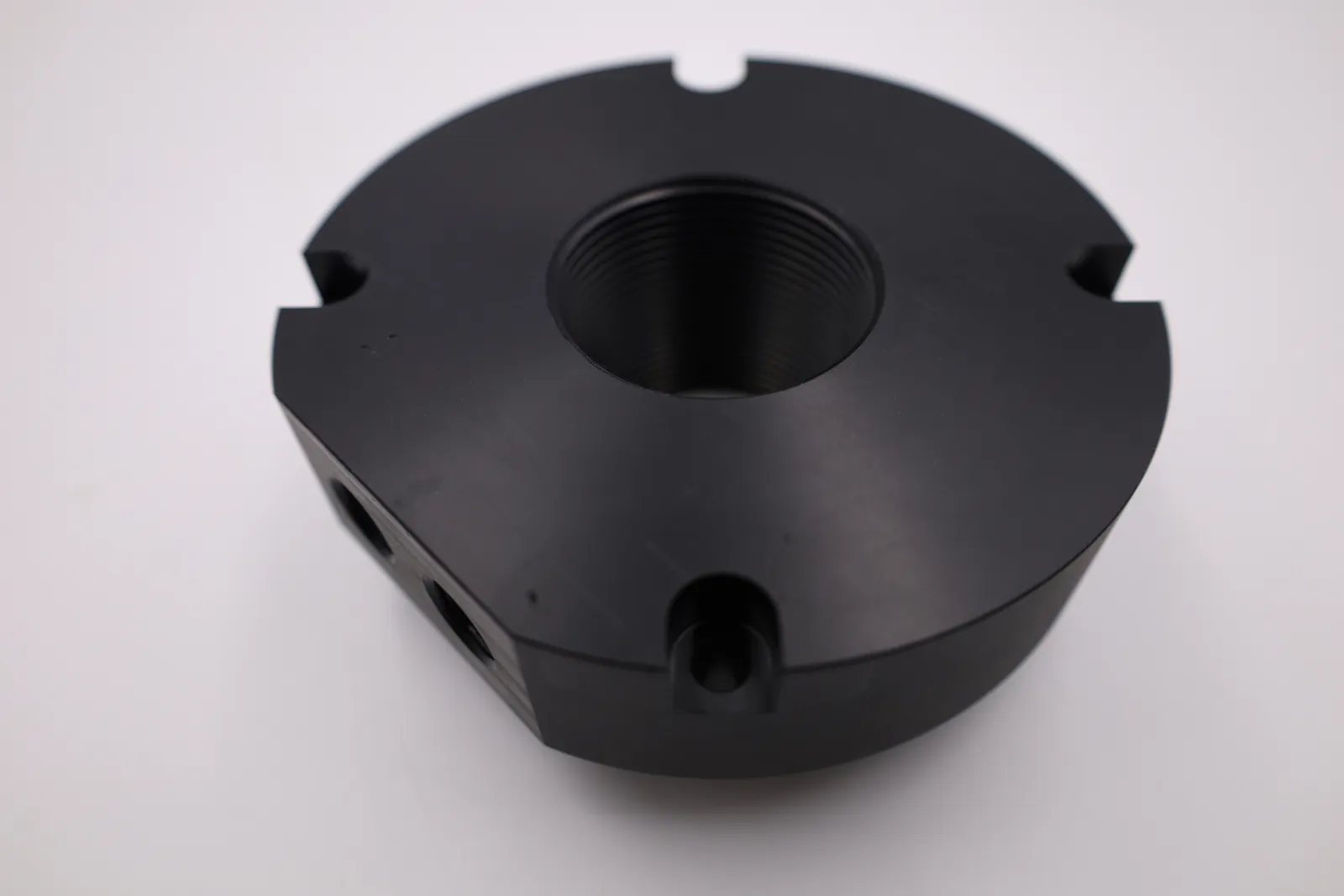 The underside of a lid: a fine thread cut right through the centre, three notches in the rim and two threaded ports in the