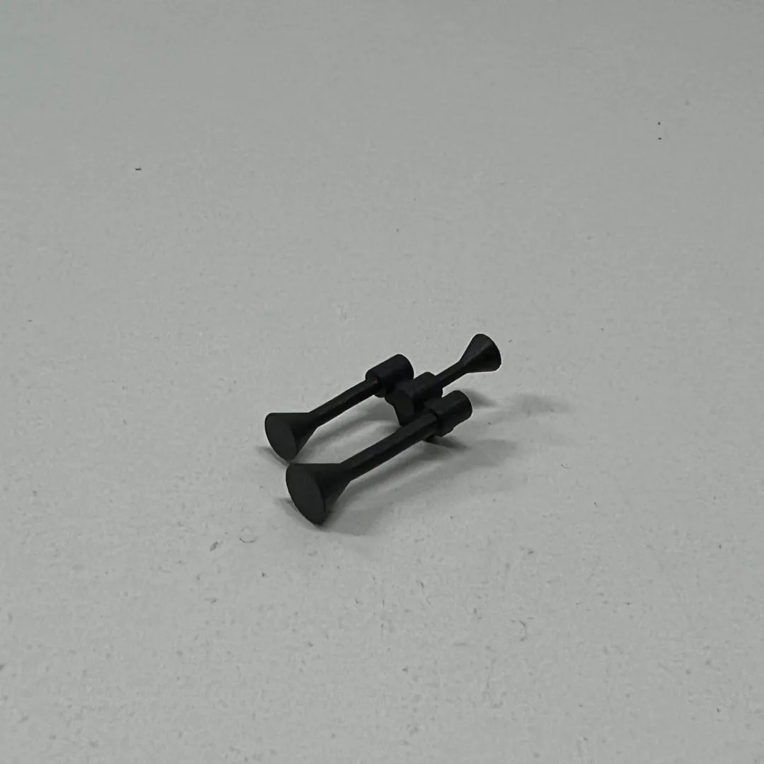 A tiny printed twin horn in dark grey, lying on its own on a white table