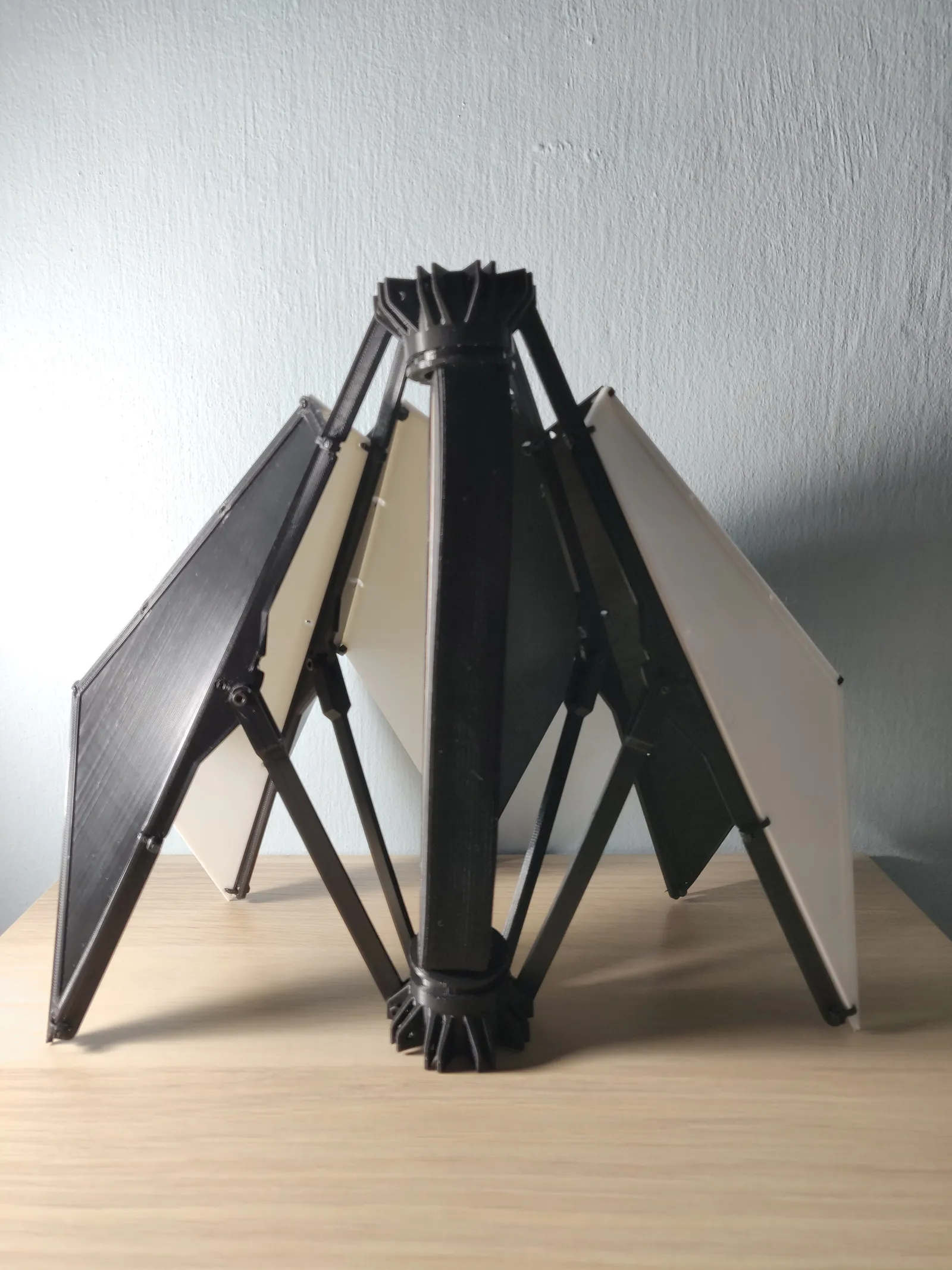 The prototype seen side on: the black central hub with a ring at each end, the printed arms running out to the black and white panels