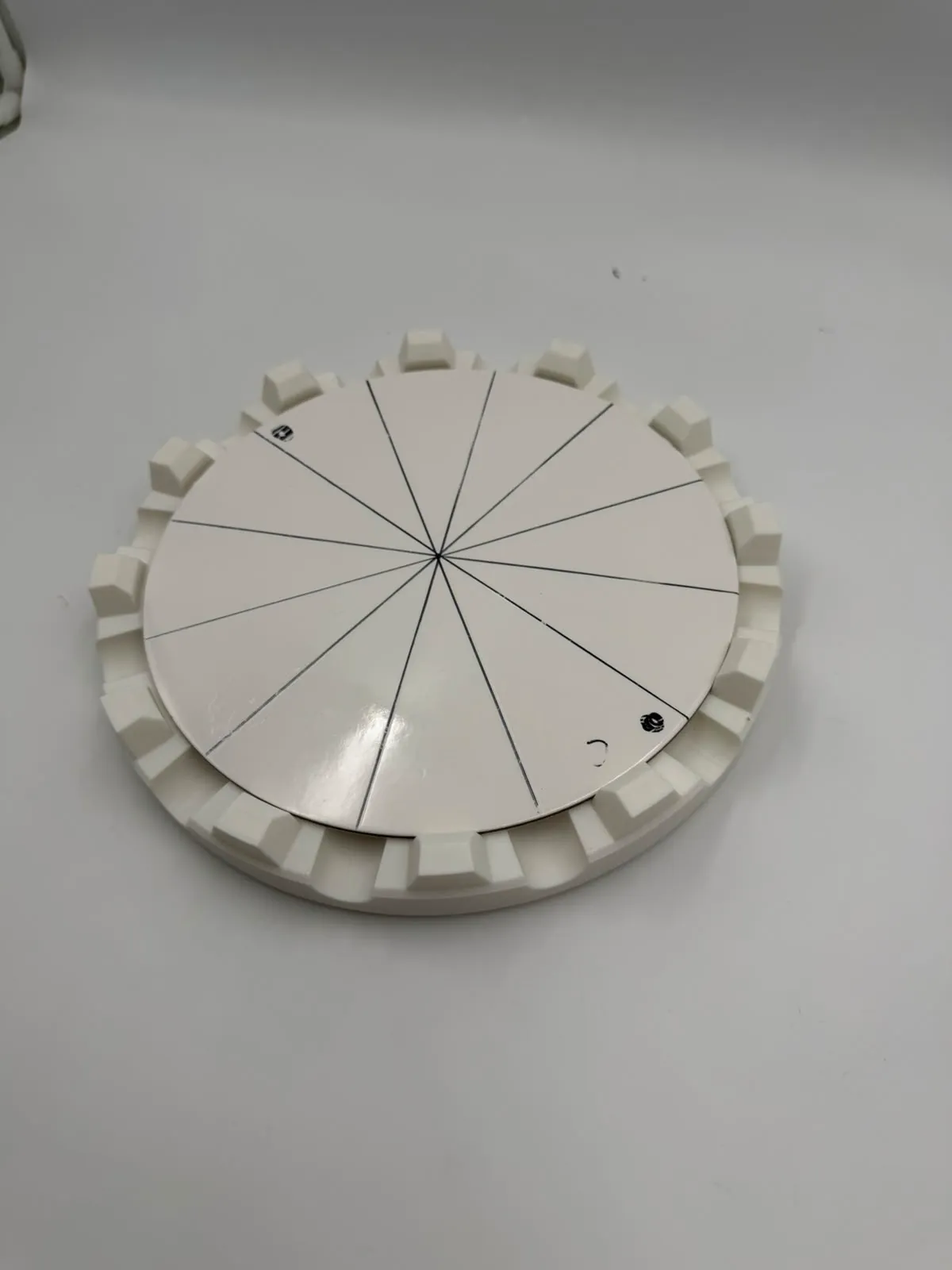 The printed holder with a white cake board seated in it, the board marked out in 12 equal slices
