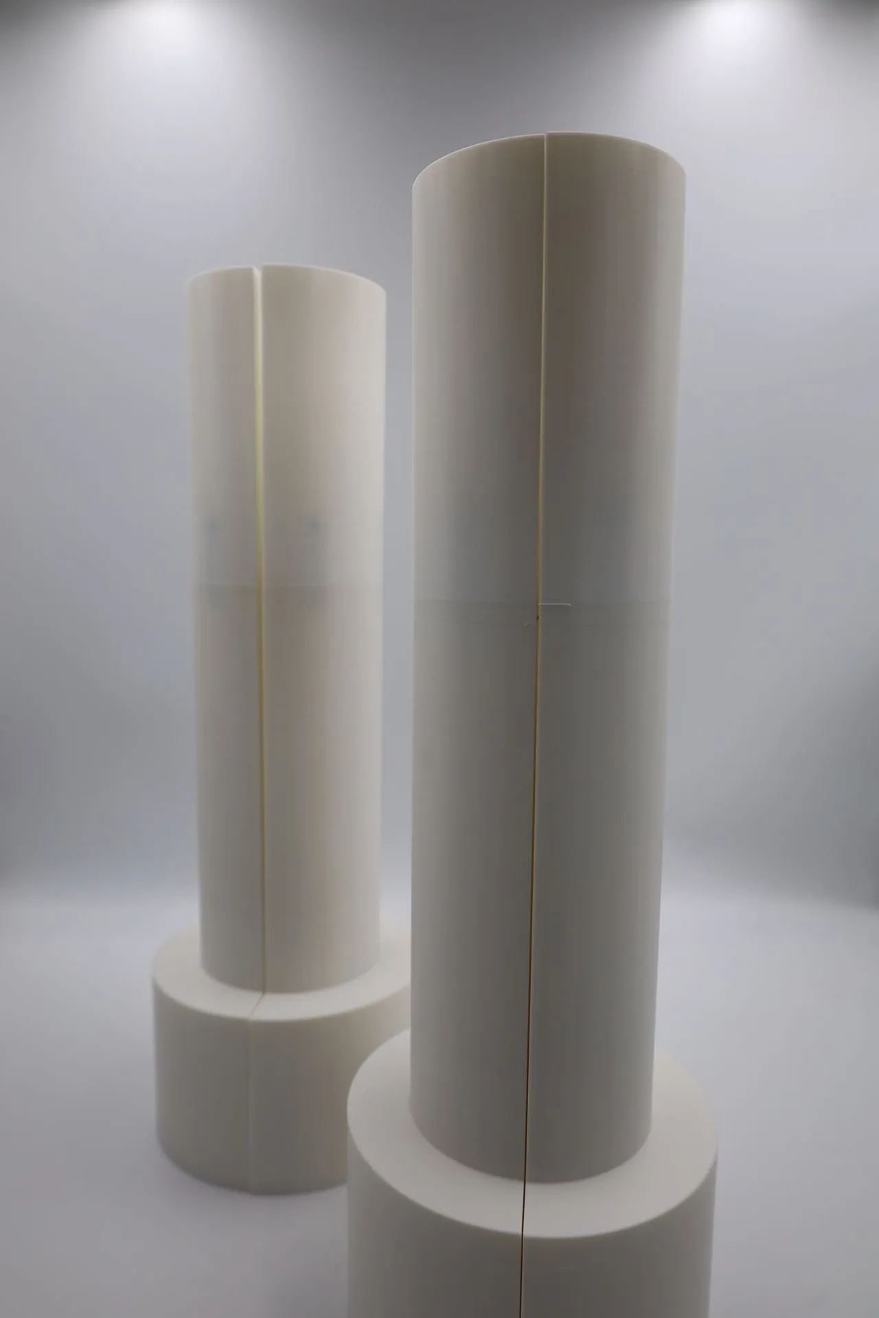 The two finished white bagel moulds standing side by side, one shorter than the other, each a tall column on a wider round base