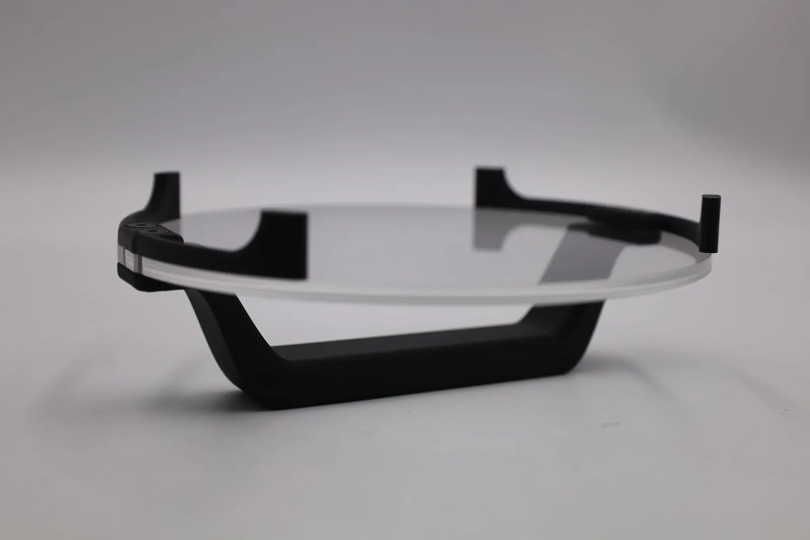 A finished cookie stamp turned upside down: the black handle underneath and the curved black feet rising from the rim of the clear disc
