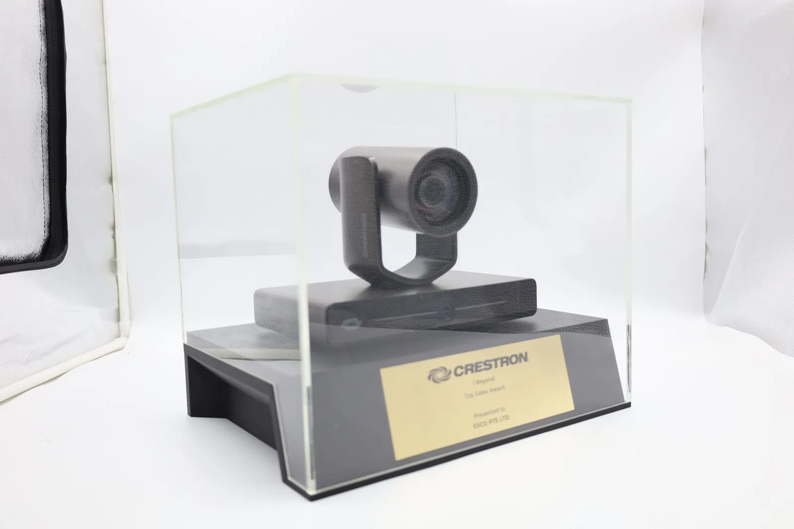The finished trophy closed in its clear acrylic case, seen from an angle, with the camera above the gold nameplate