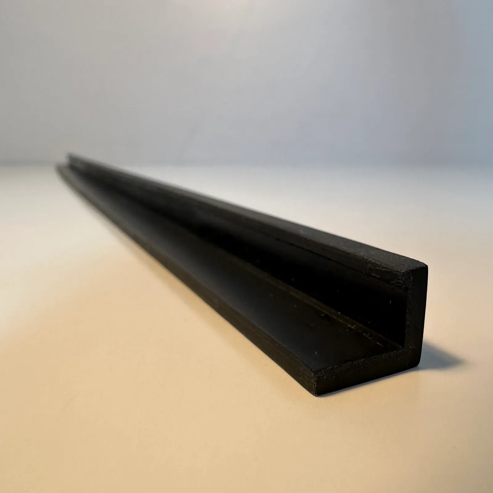Close view of the end of the black strip: the right angle, the lip folded over at the top of the upright and the fine print lines on the end face