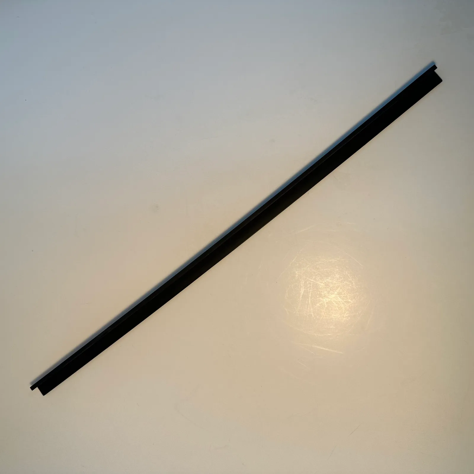 The black angle trim strip from above at the opposite angle, the open side of the channel facing up