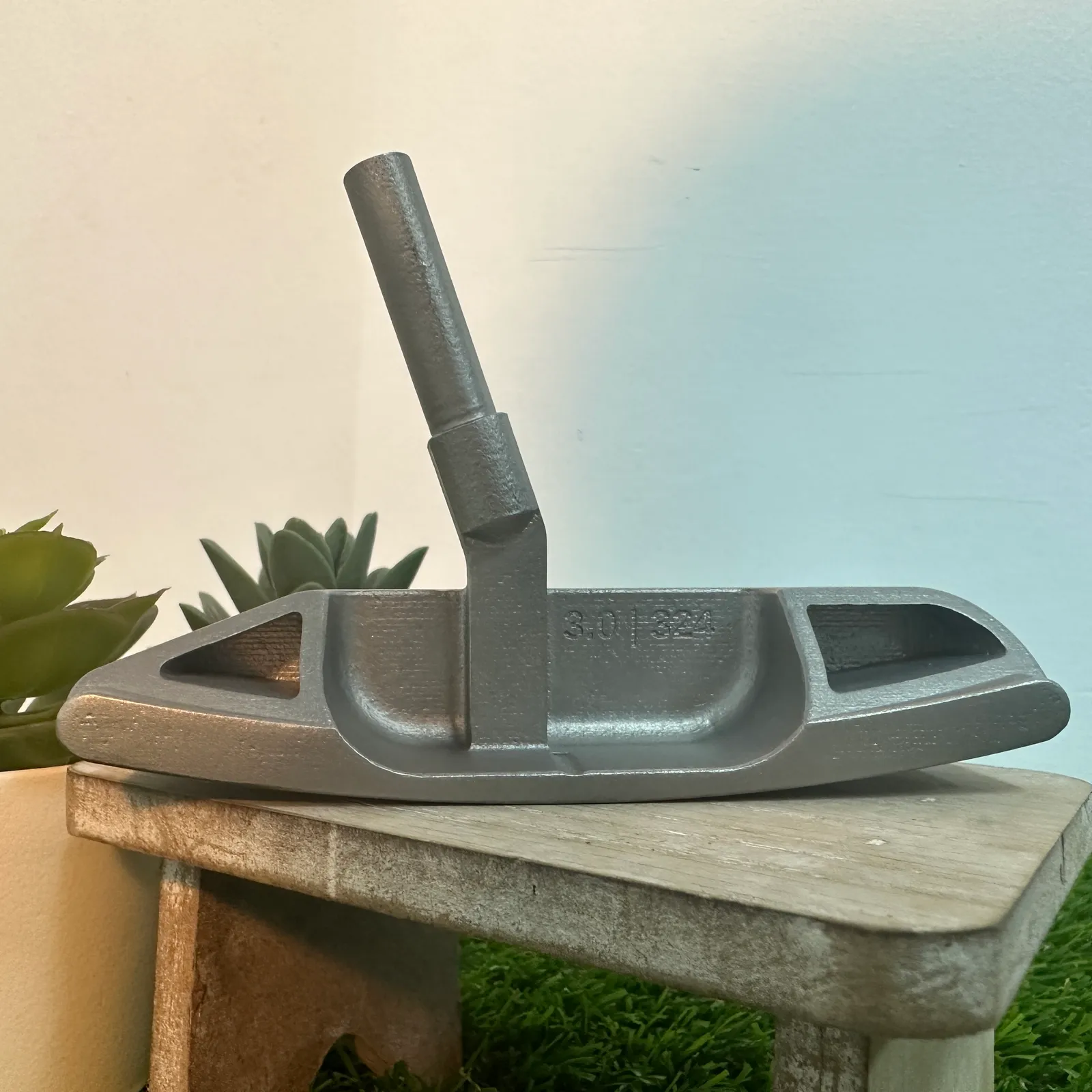 The finished silver putter head on a wooden stand, seen from the back: the hosel post rising from the heel side, a pocket at each end and 3.0 | 324 marked in the middle