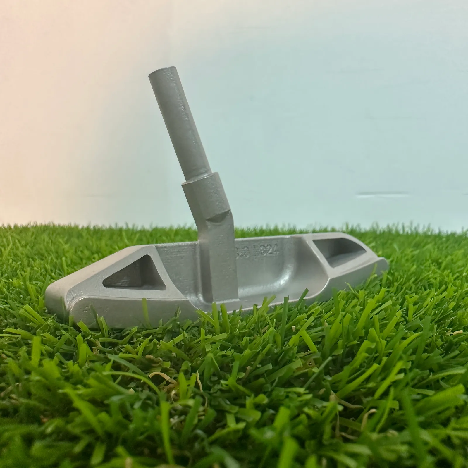 The printed putter head standing on artificial grass, seen from the back, with the hosel post, both pockets and the 3.0 | 324 marking