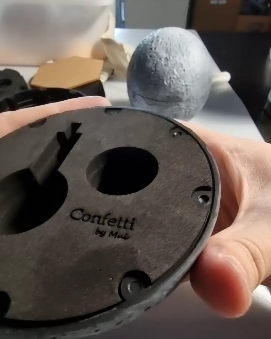 Hands fitting the top foam layer, printed with the Confetti by Mui logo, into a painted half of the moon