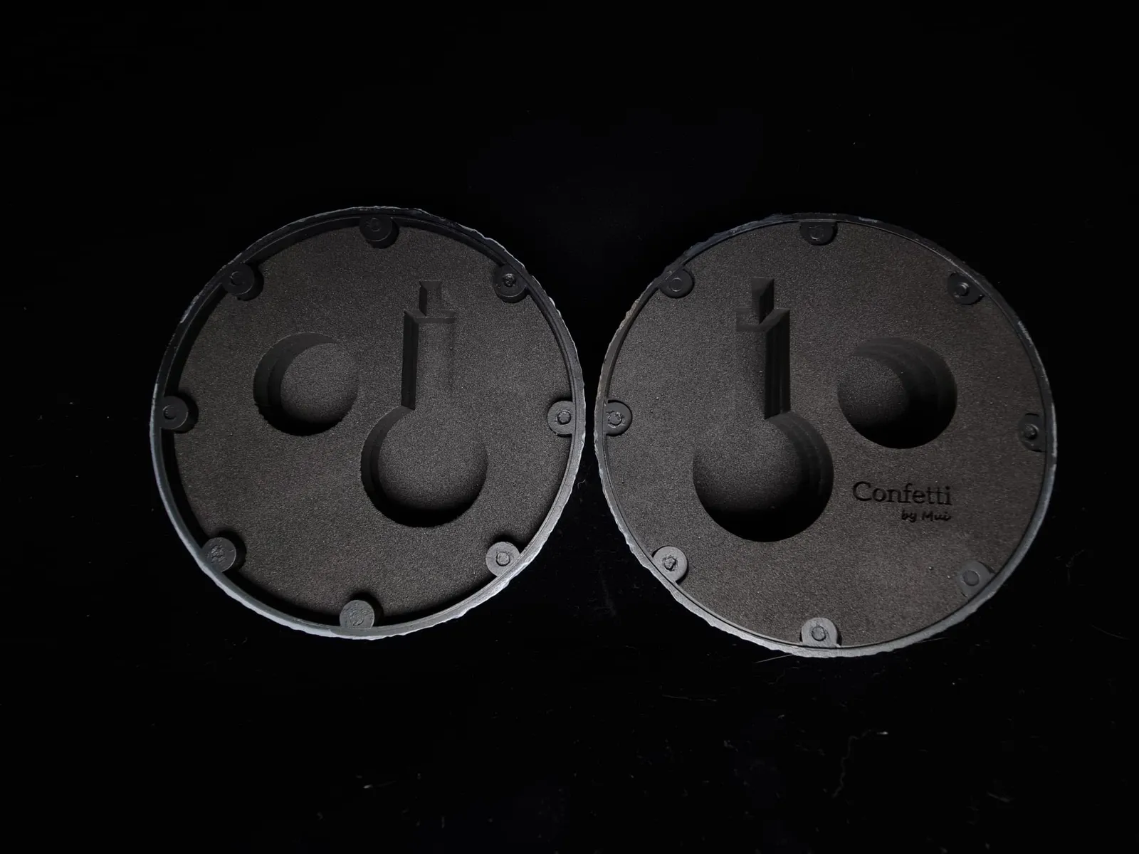 The two open halves seen face on against black, the foam pockets lined up and the Confetti by Mui logo on one insert