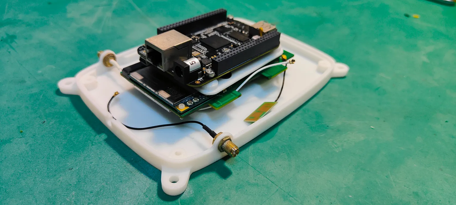 The board stack seated in the white printed base, with thin leads running to a brass antenna port in the side