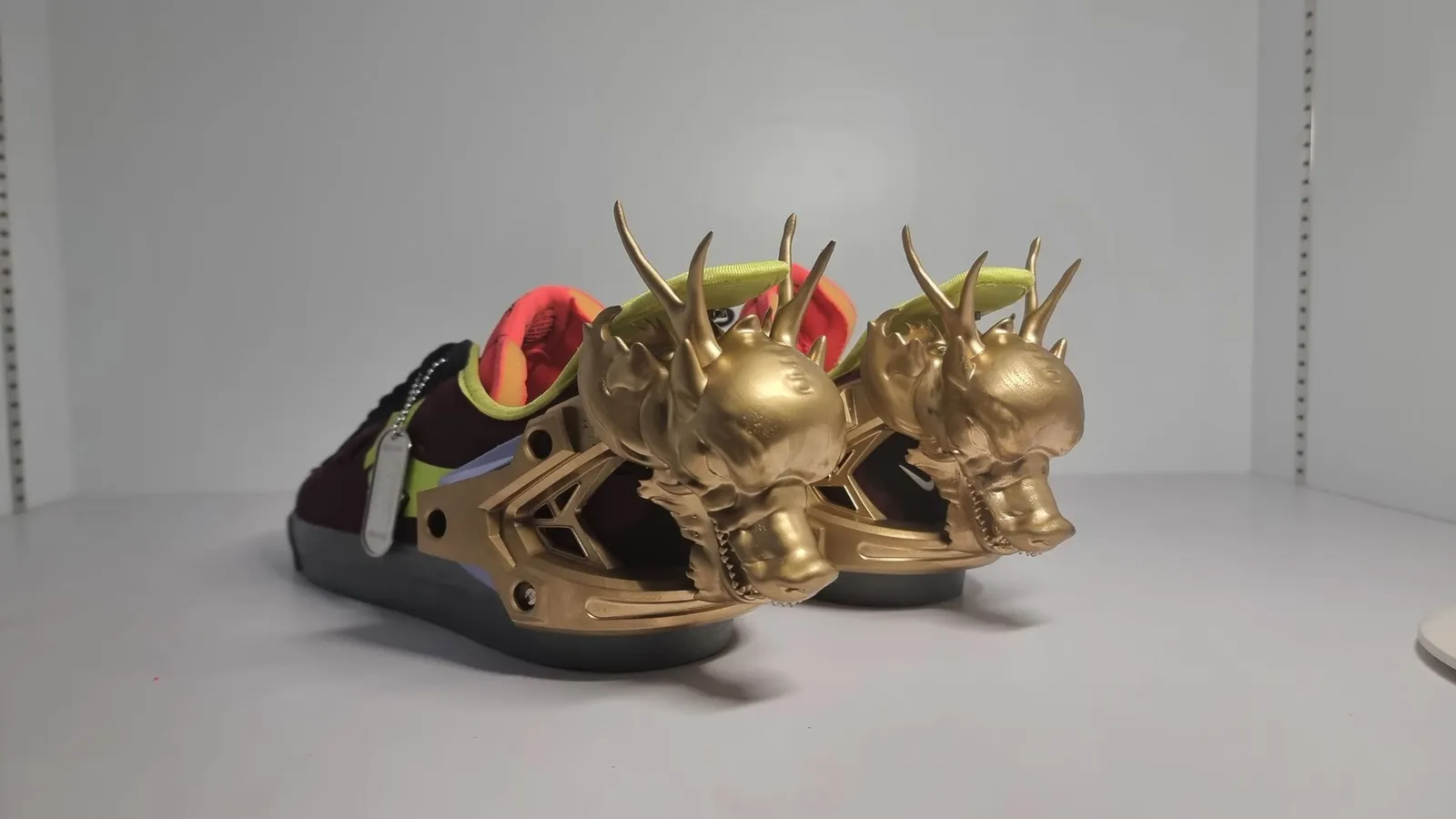 The trainers seen from behind, two gold dragon heads side by side above the heels with jaws open
